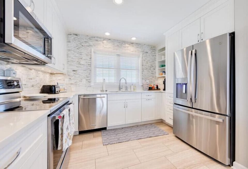 Cook your favorite meals in this bright, modern kitchen with sleek stainless steel appliances, elegant tile backsplash, and plenty of counter space to prepare everything you need.