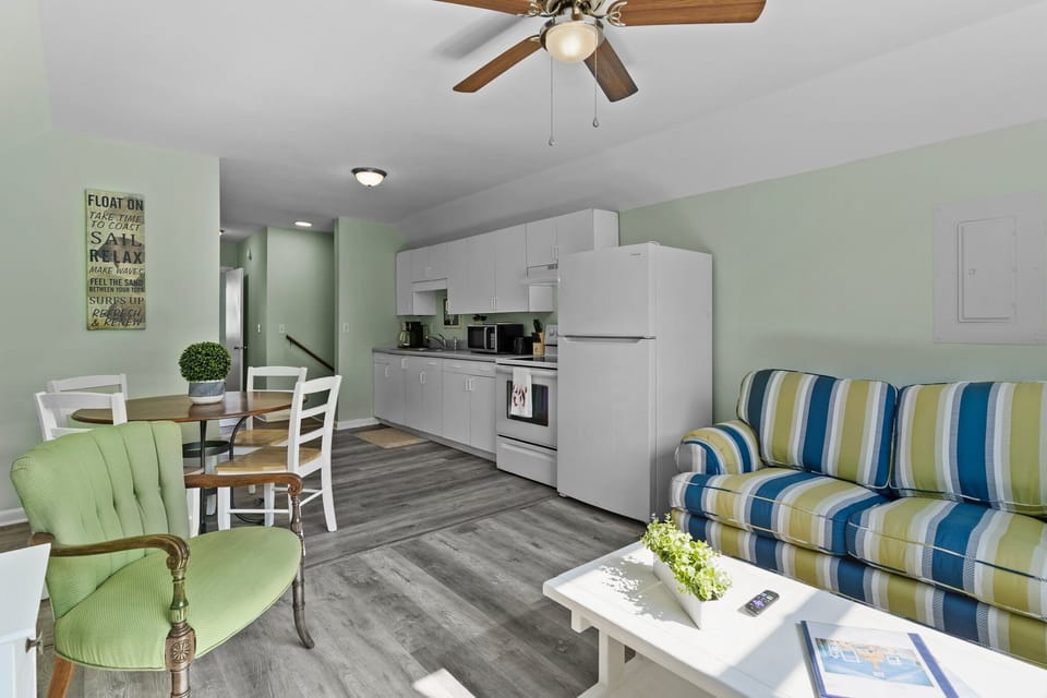 Your bright, open living space flows seamlessly from cozy striped sofa to fully-equipped kitchen, perfect for relaxing after beach days.