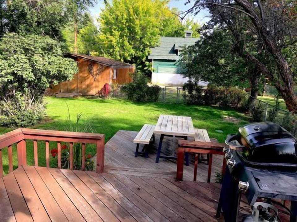 Large backyard feels like an oasis with a deck, outdoor dining space and gas grill