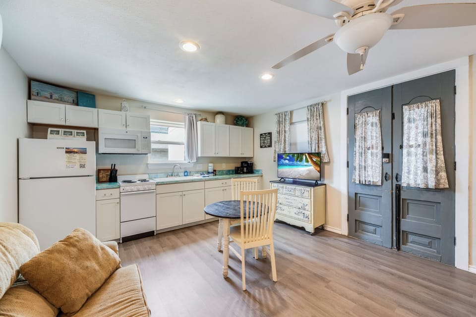 Step into your cozy coastal retreat where the open kitchen invites you to whip up beachside meals, while the breezy ceiling fan and charming seating area make every moment feel like home.
