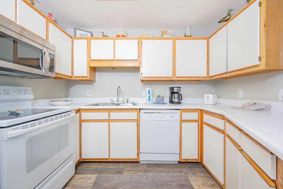 Bright kitchen featuring white countertops, wood cabinetry, and essential appliances, perfect for preparing meals