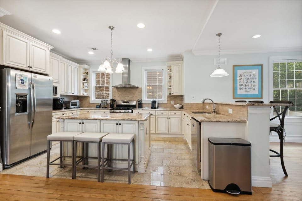 View of kitchen, island, and fridge, facing east, showing all major appliances.