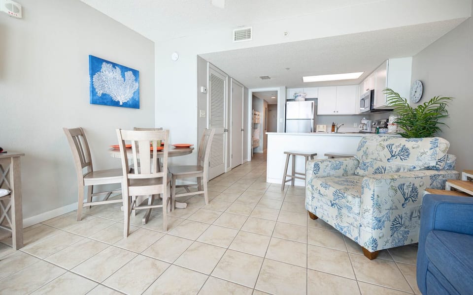 Enjoy meals at the round dining table or relax on the floral armchair in this airy living space with tile flooring