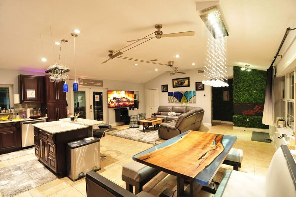 Open-concept living and dining with live-edge wood river table, kitchen island, green living wall and pendant lighting, Orlando
