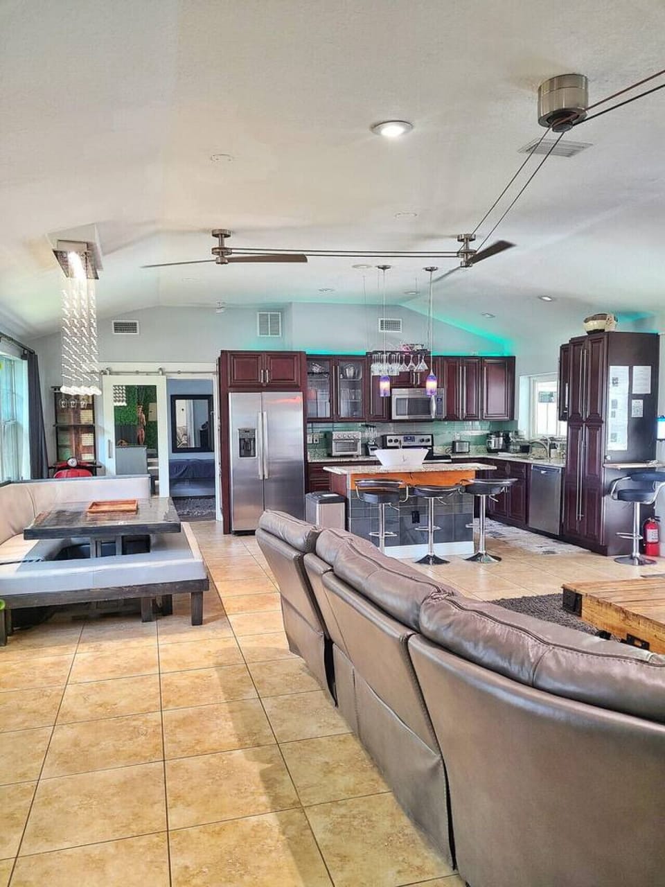Spacious kitchen and living area with dark wood cabinets, stainless steel appliances, large pendant lights and sectional sofa, Orlando
