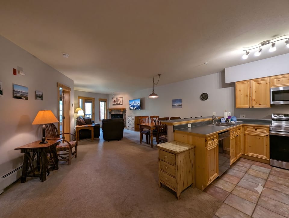 Spacious open-plan retreat where rustic wood meets modern comfort. Dining area, cozy fireplace lounge, and fully equipped kitchen flow together for effortless mountain living.