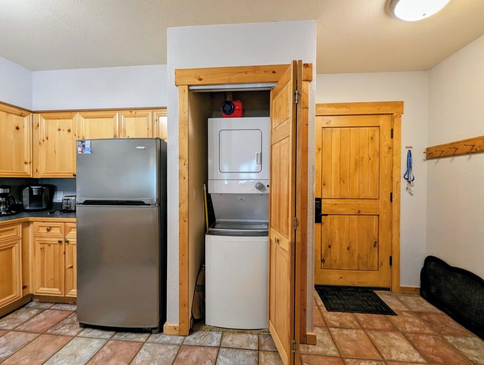 A fully equipped kitchen with warm pine cabinetry and the added convenience of in-unit laundry—washer and dryer tucked right into a built-in nook, making your stay comfortable and hassle-free.