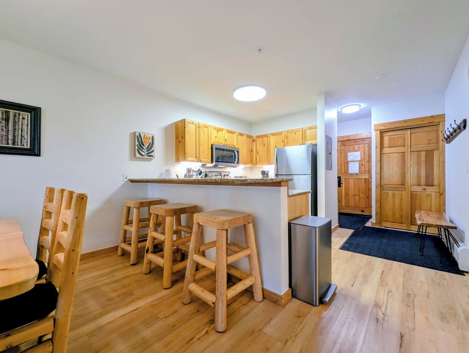 Cozy mountain retreat with warm wood accents, handcrafted bar stools, and pine cabinetry. Open kitchen perfect for cooking and entertaining with ample storage.