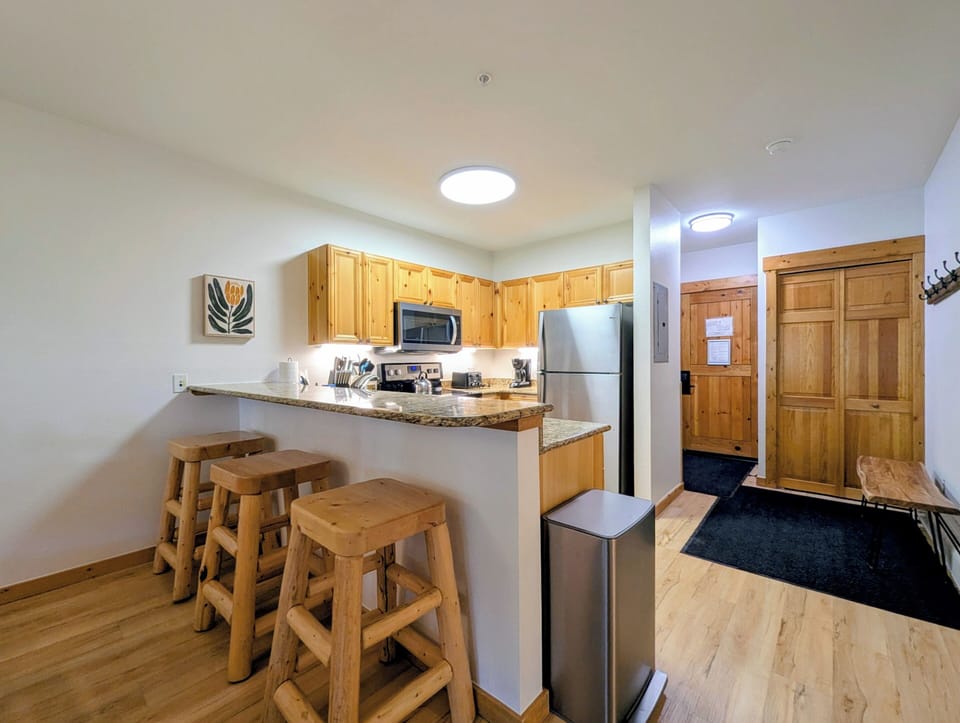 Your fully equipped kitchen awaits with warm wood cabinetry, granite counters, and stainless appliances—plus a cozy breakfast bar for casual meals and morning coffee.