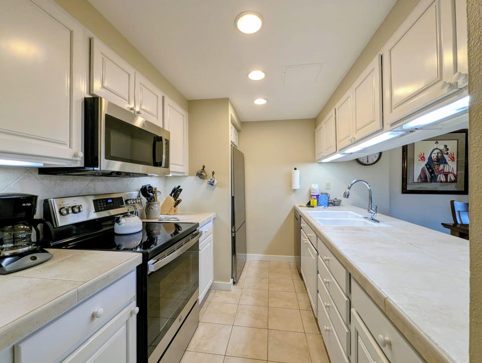 Your spacious galley kitchen features crisp white cabinetry, modern stainless appliances, and plenty of counter space for preparing meals during your stay.
