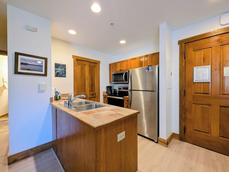 Your spacious kitchen features warm wood cabinetry, stainless steel appliances, and a breakfast bar perfect for morning coffee or casual meals.