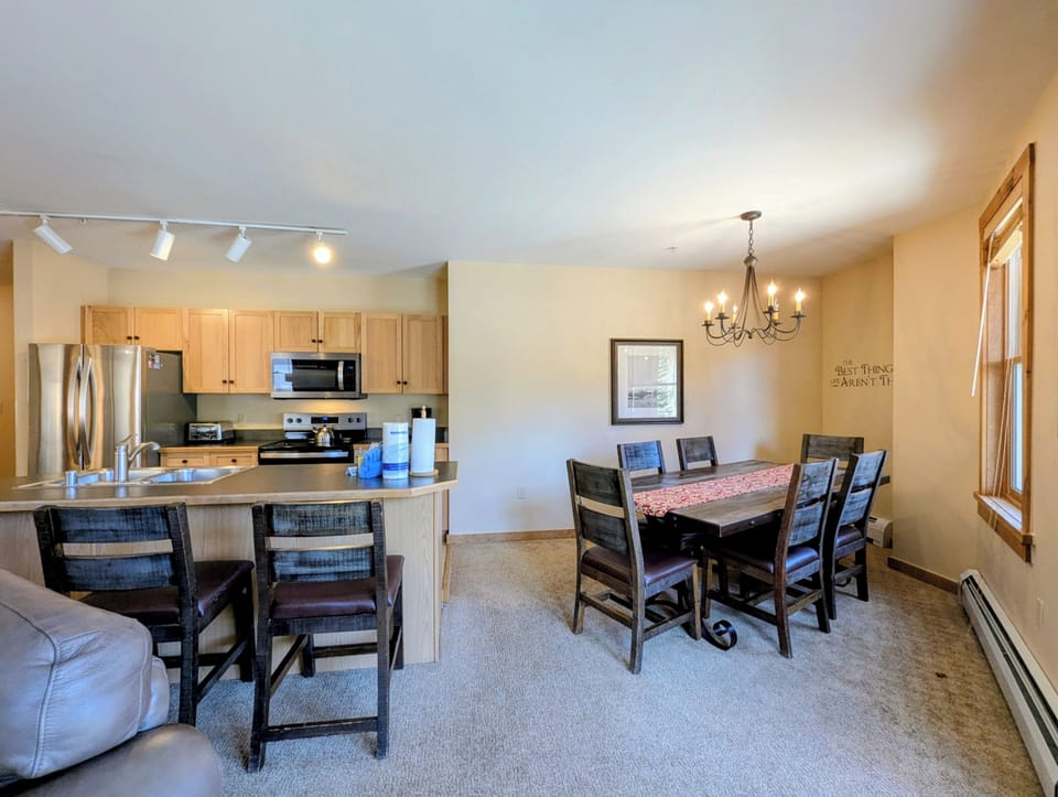 Your open-concept space features warm wood cabinetry, stainless-steel appliances, and a breakfast bar that flows into a cozy dining area—perfect for gathering after a day exploring.