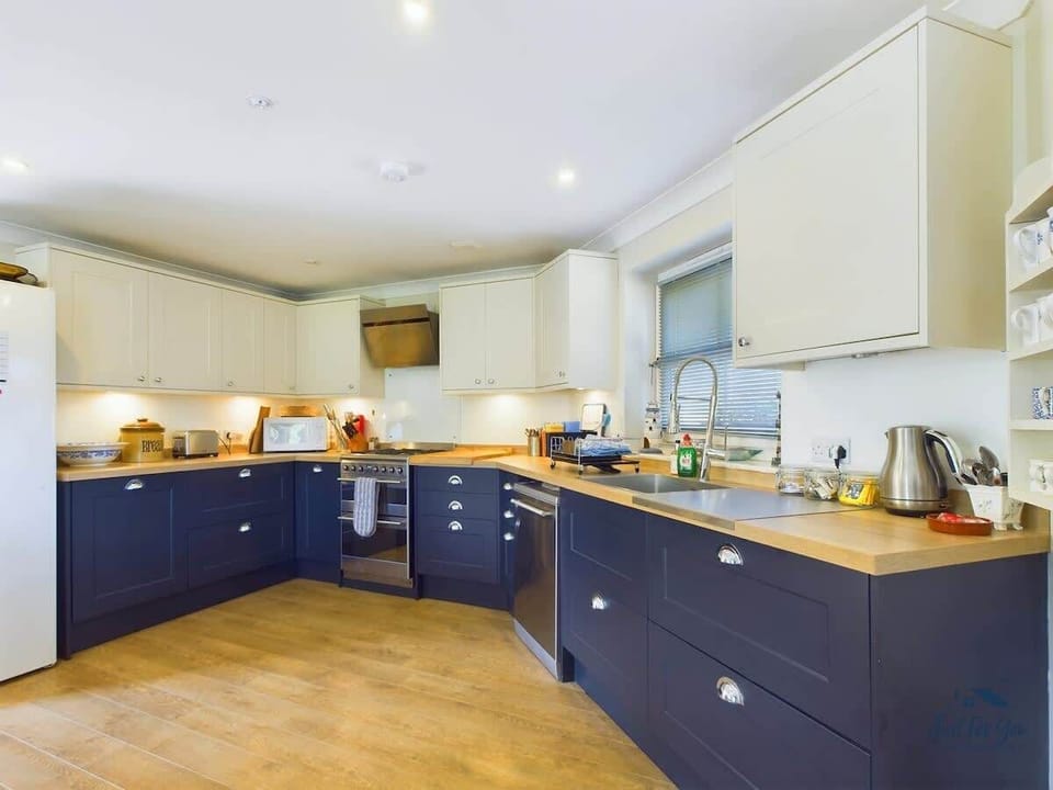 A high-spec, modern kitchen with integrated appliances, including an oven, hob, and dishwasher.