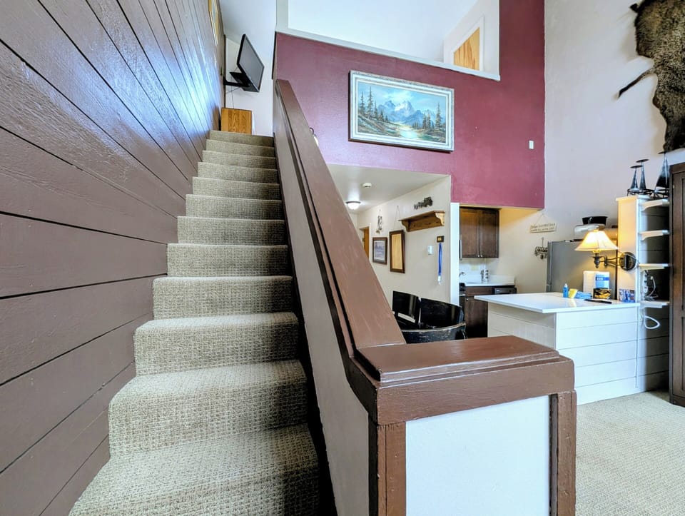 Step into your cozy mountain retreat where rustic charm meets modern comfort, with carpeted stairs leading to your private loft bedroom.