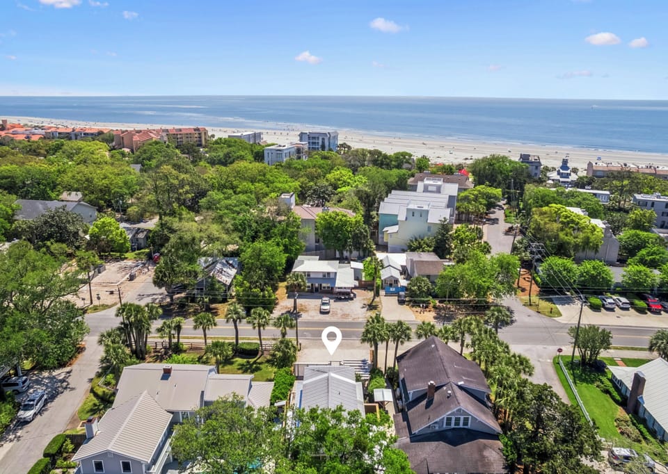 Aerial view shows this beachside property nestled among lush trees, just moments from pristine sandy shores and sparkling ocean waters.