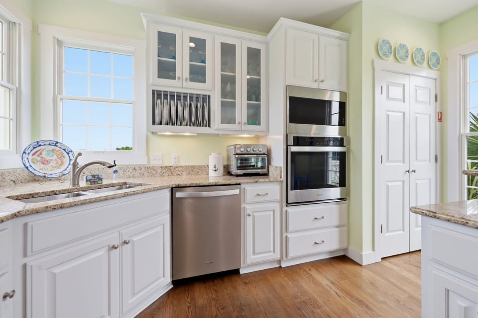 Step into this bright, welcoming kitchen where you'll find gleaming granite countertops, stainless steel appliances, and soft coastal breezes through sunny windows. Your culinary adventures await in this spotless, fully-equipped space.