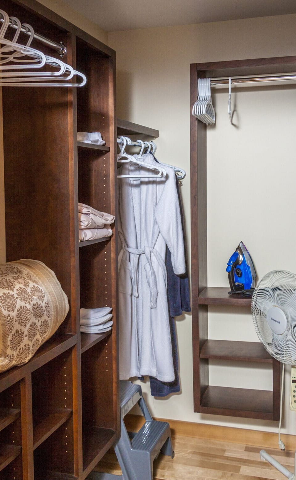 Master bedroom walk-in closet with iron, ironing board, and robes