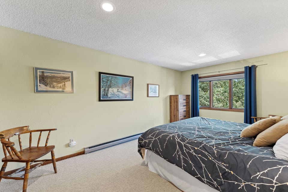 Unwind in your peaceful bedroom with comfortable bedding, charming artwork, and a cozy reading chair by the garden-view window.