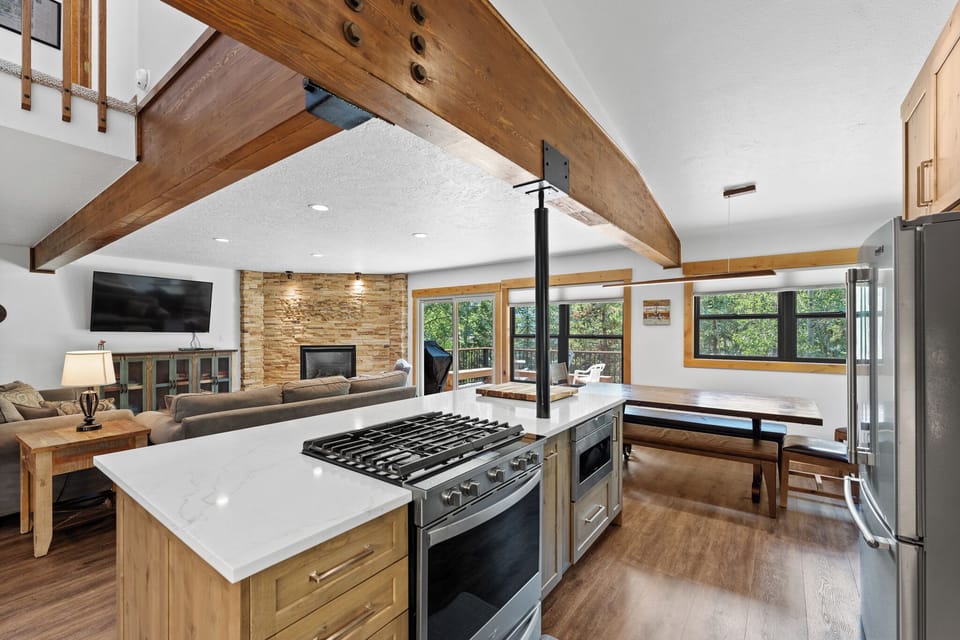 Your open-concept kitchen flows seamlessly into the living area, where rustic beams meet modern amenities for perfect gathering moments.