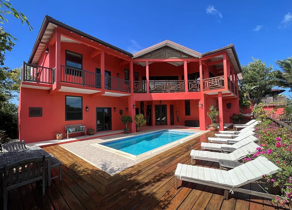 Rear of villa, pool deck with 8 loungers, teak dining table, & sunbed with cover