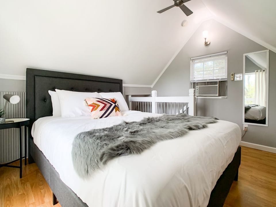 Bright and airy upstairs bedroom featuring a cozy queen size bed, Smart TV and access to the balcony to relax on after a long day.