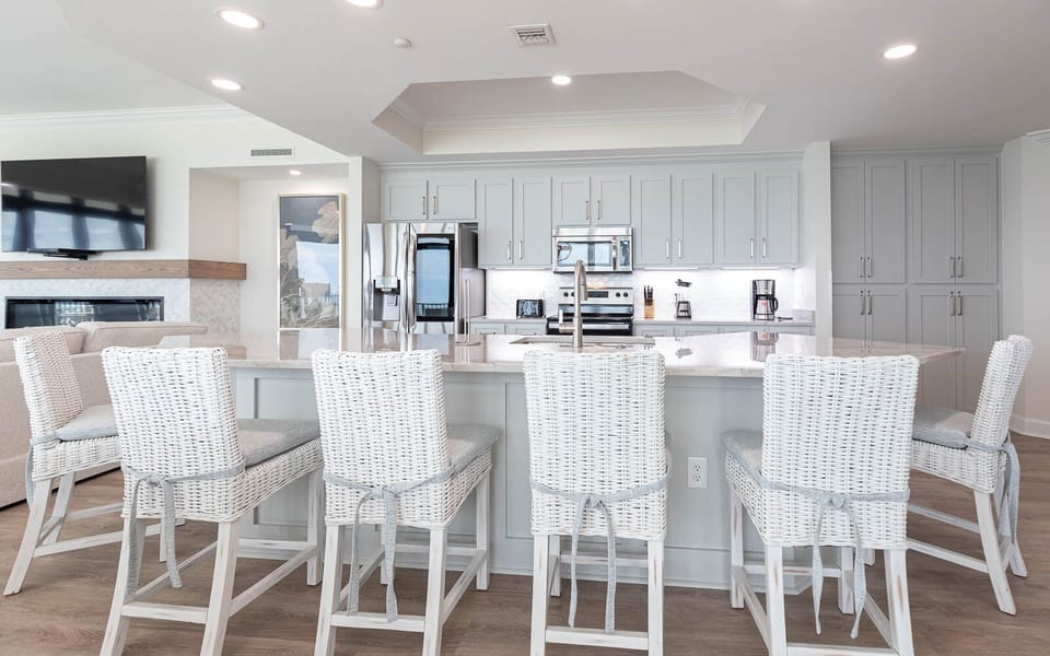 The modern kitchen features stainless appliances, a coffee maker, and inviting white cabinetry, perfect for gatherings