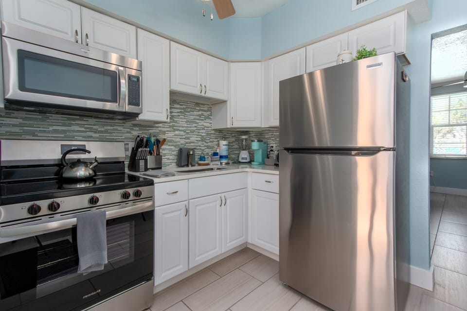 Kitchen: Features brand new stainless steel appliances including large fridge, stove, oven, kettle, blender, coffee maker, and microwave.