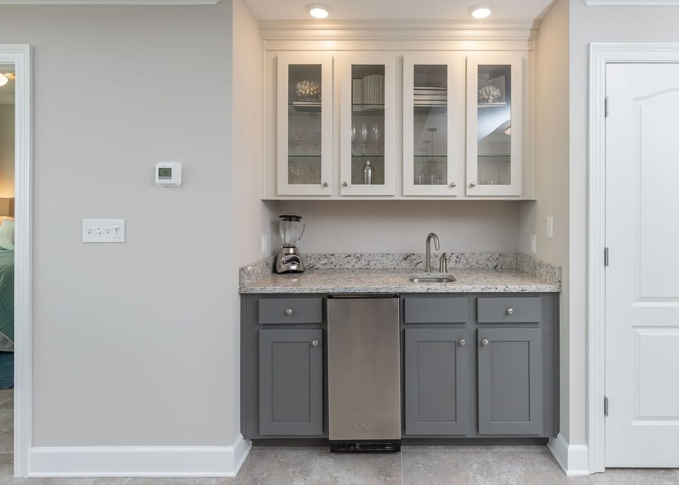 Craft refreshing drinks at the wet bar, enjoying easy access to glassware for memorable gatherings