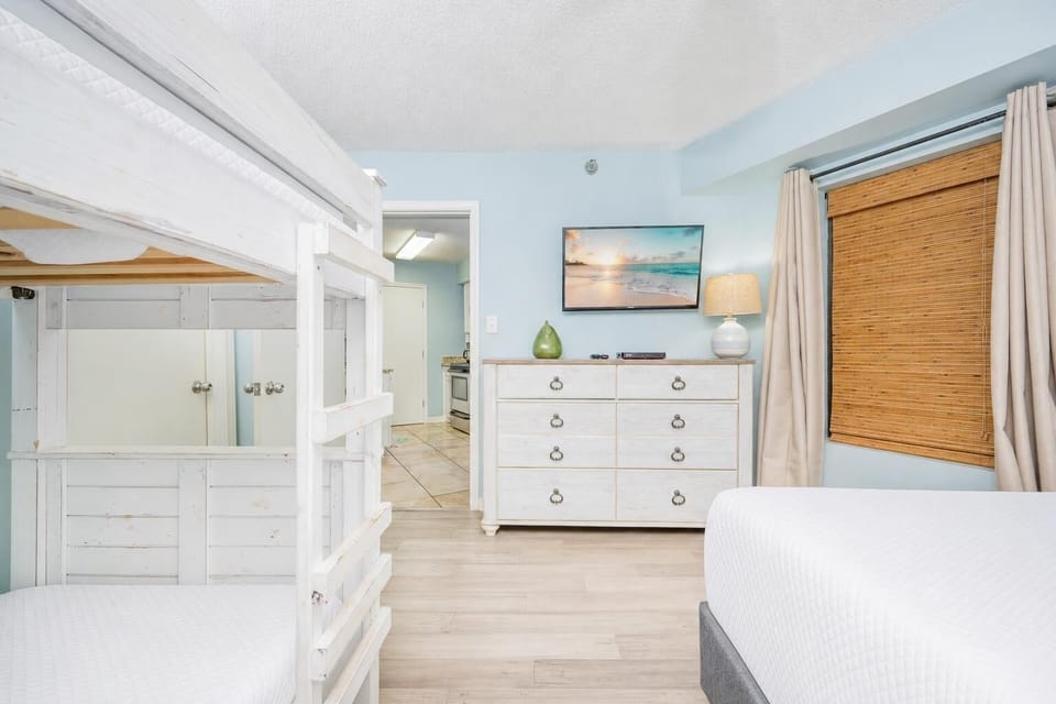 Inviting guest bedroom featuring a cozy twin bunk bed, full bed, dresser, and a wall-mounted TV for entertainment