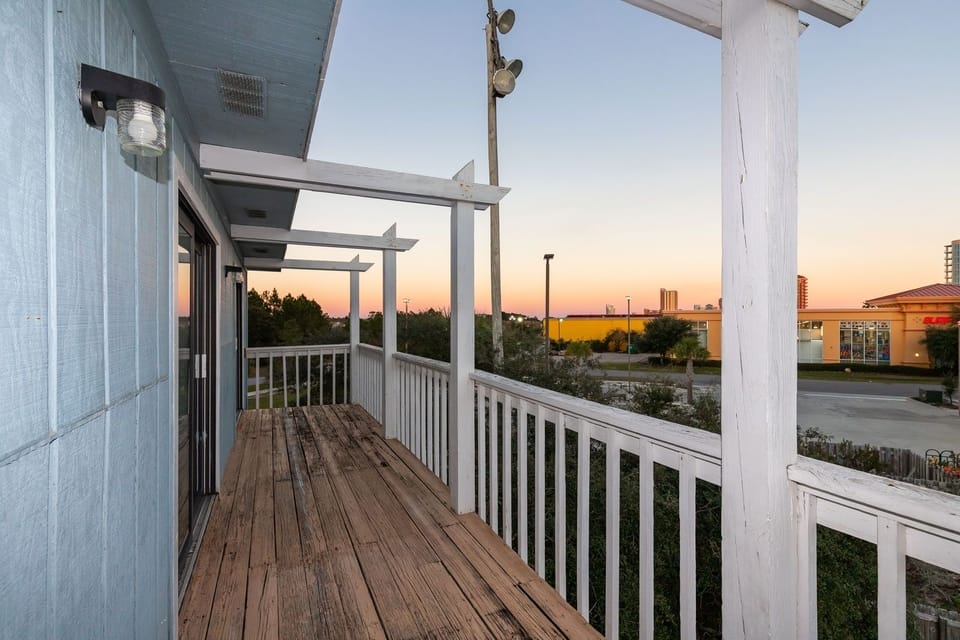 This balcony offers a relaxing outdoor space with a wooden deck and a lovely view of the evening sky