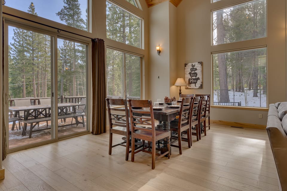 - Dining area with forest views through tall windows and doors  
- Large wooden table perfect for shared meals with family  
- Easy access to outdoor deck for indoor and outdoor dining