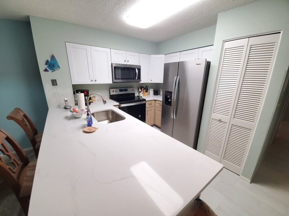 Modern kitchen with spacious marble counters and stainless steel appliances.