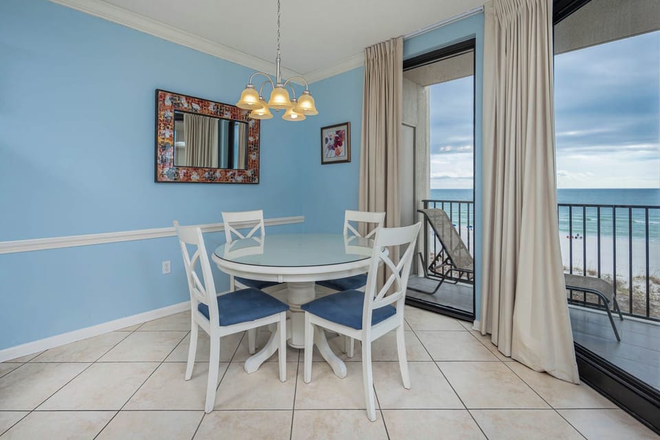 Dine at the round table with beach views, surrounded by soft blue walls and natural light from expansive windows
