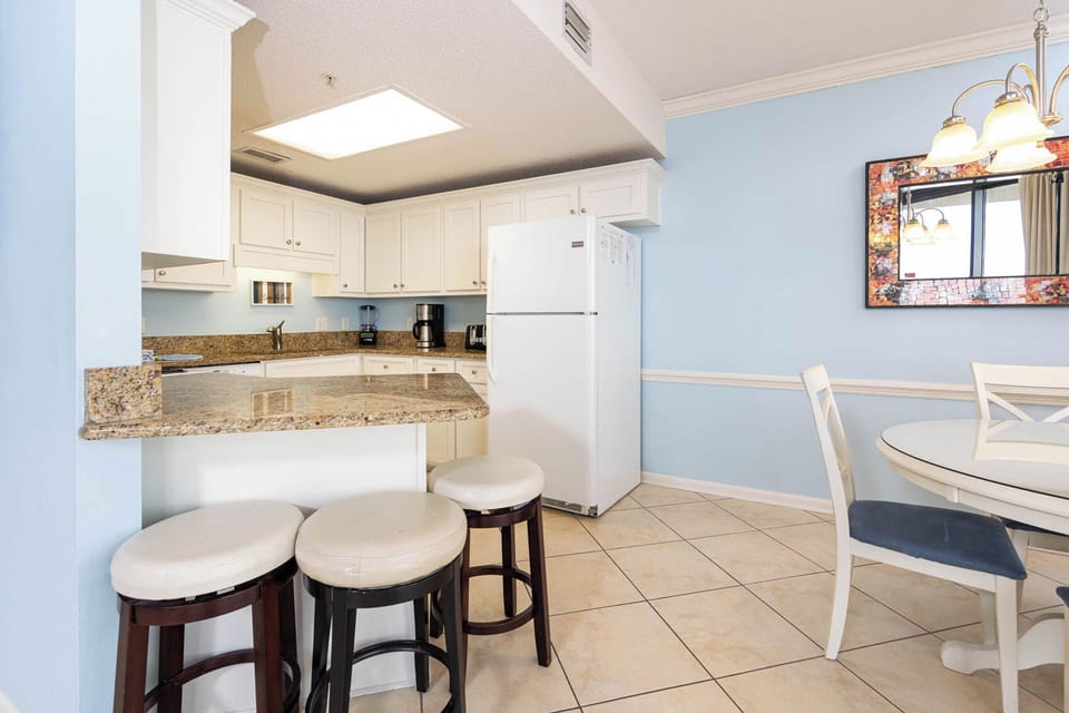 Enjoy cooking in the bright kitchen with granite countertops, white appliances, and a cozy breakfast bar