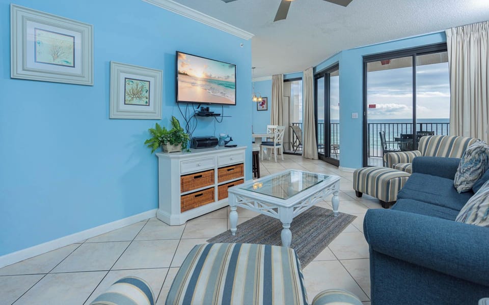 Relax in the airy living area featuring a large TV, sofa with queen sleeper, and views of the beach