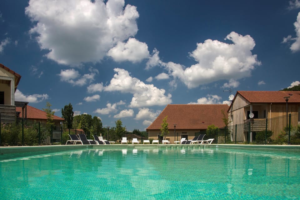 Dive into relaxation by the shimmering pool, surrounded by lush greenery and blue skies.