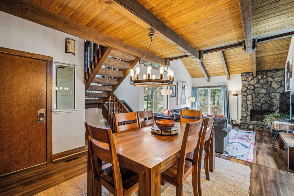 Step into this inviting open-concept space where vaulted wood ceilings and natural light create a warm, welcoming ambiance. Gather around the handcrafted dining table, cozy up by the stone fireplace, and feel right at home.