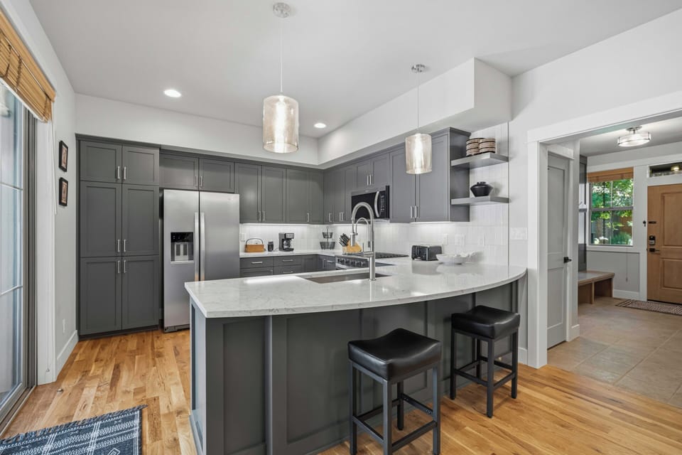 Your modern chef's kitchen features sleek gray cabinetry, gleaming stainless steel appliances, and a spacious marble island perfect for morning coffee or meal prep.