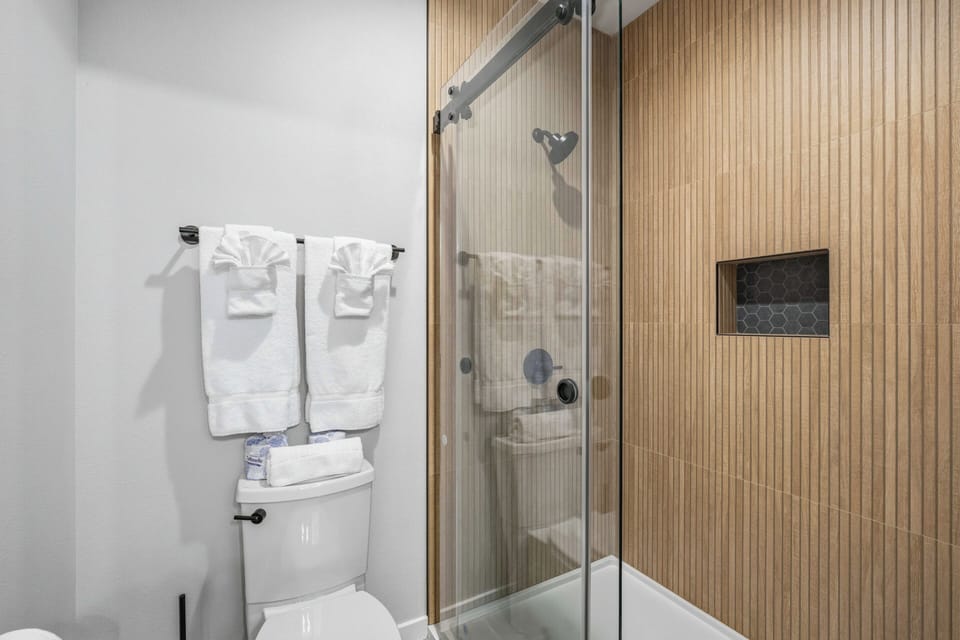 Step into your private bathroom featuring a sleek glass-enclosed shower and fresh white towels awaiting your arrival after exploring the area.