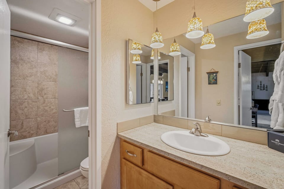 Your private bathroom features warm pendant lighting, ample counter space, and a tub-shower combo—perfect for unwinding after a mountain adventure.