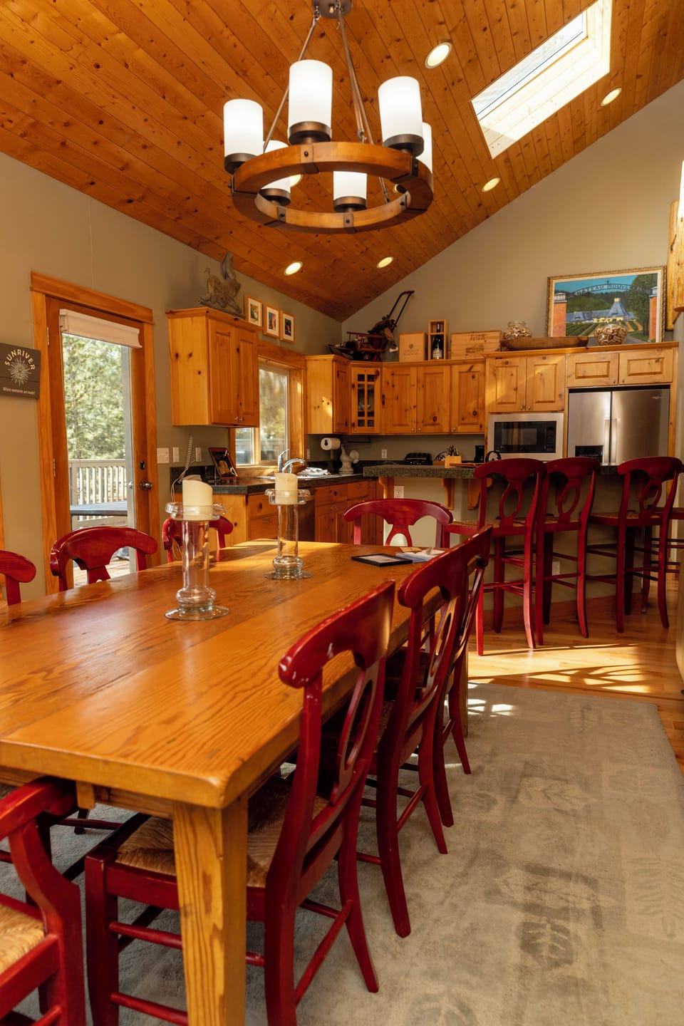 Your spacious kitchen welcomes you with warm wood accents, vaulted ceilings, and red chairs perfect for family meals together.