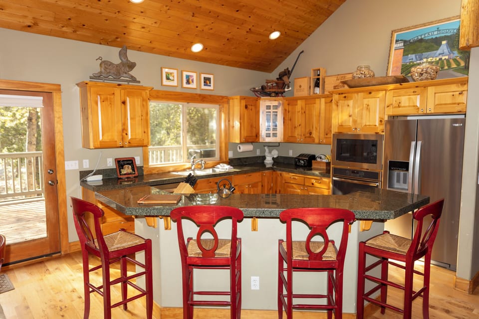Cook together in this charming mountain kitchen featuring granite counters, rustic wood cabinets, and a breakfast bar perfect for morning coffee.