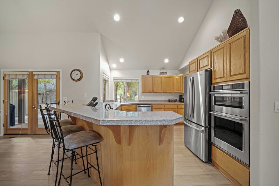Your spacious chef's kitchen features granite countertops, stainless steel appliances, and a breakfast bar perfect for morning coffee with garden views.