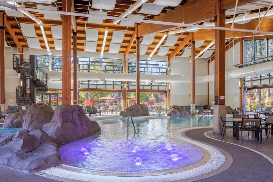 Unwind in the illuminated hot tub surrounded by natural rock features, then take a dip in the adjacent pool—all under dramatic timber beams and bright skylights.
