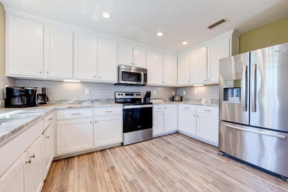 Your fully-equipped kitchen awaits with gleaming stainless appliances, spacious granite counters, and bright white cabinetry—perfect for preparing family meals or morning coffee in your home away from home.