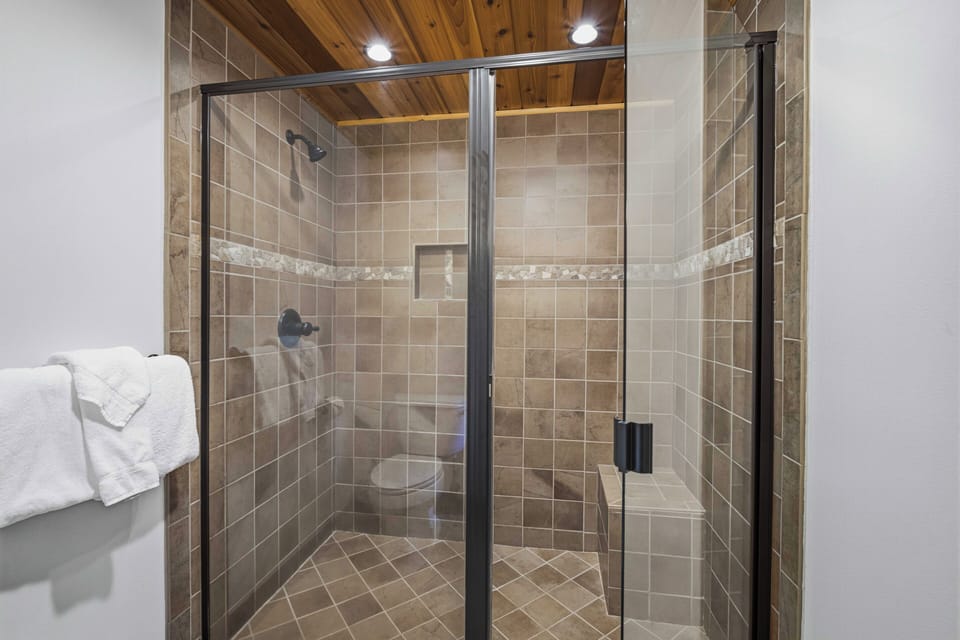Your private bathroom features a spacious walk-in shower with warm tile and a built-in bench—perfect for unwinding after a day of adventure.