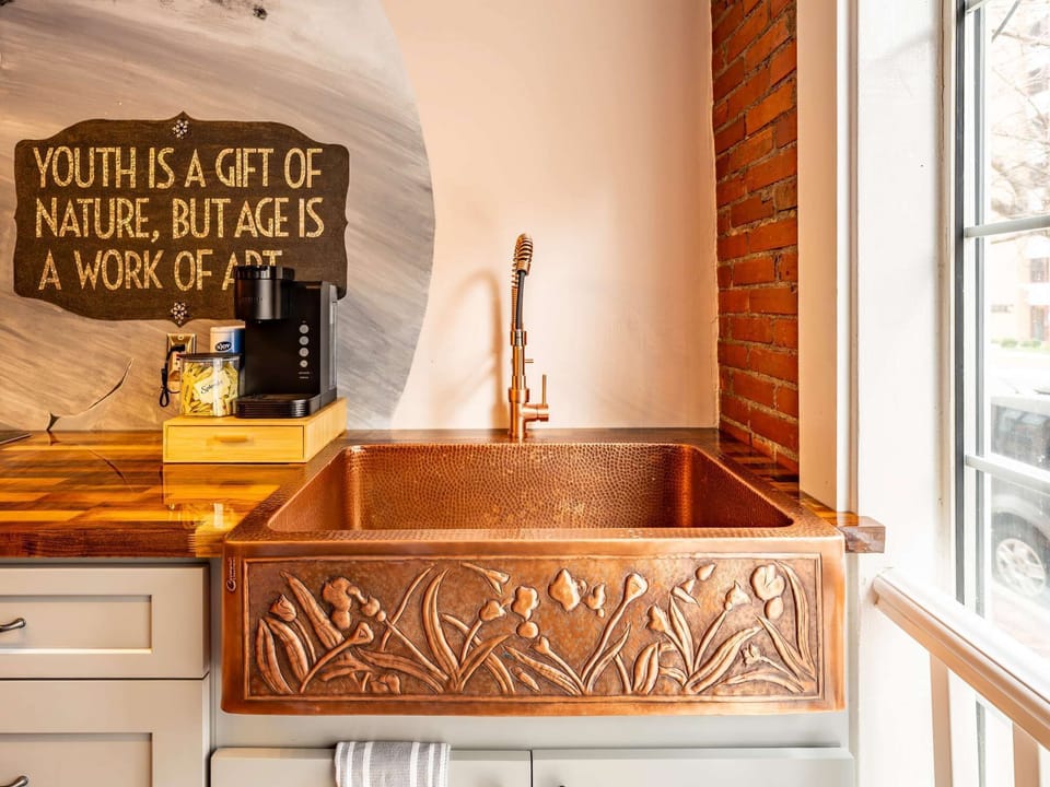 Copper farmhouse sink &amp; warm wood accents create a charming kitchen detail