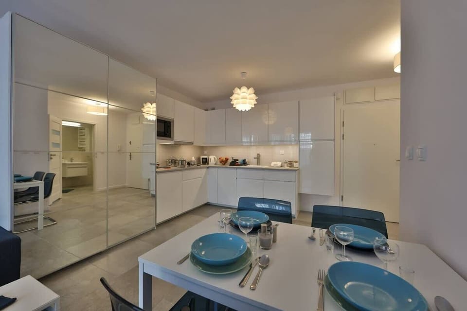 A close-up of a dining table set with plates, glasses, and cutlery, located in a minimalist living space.