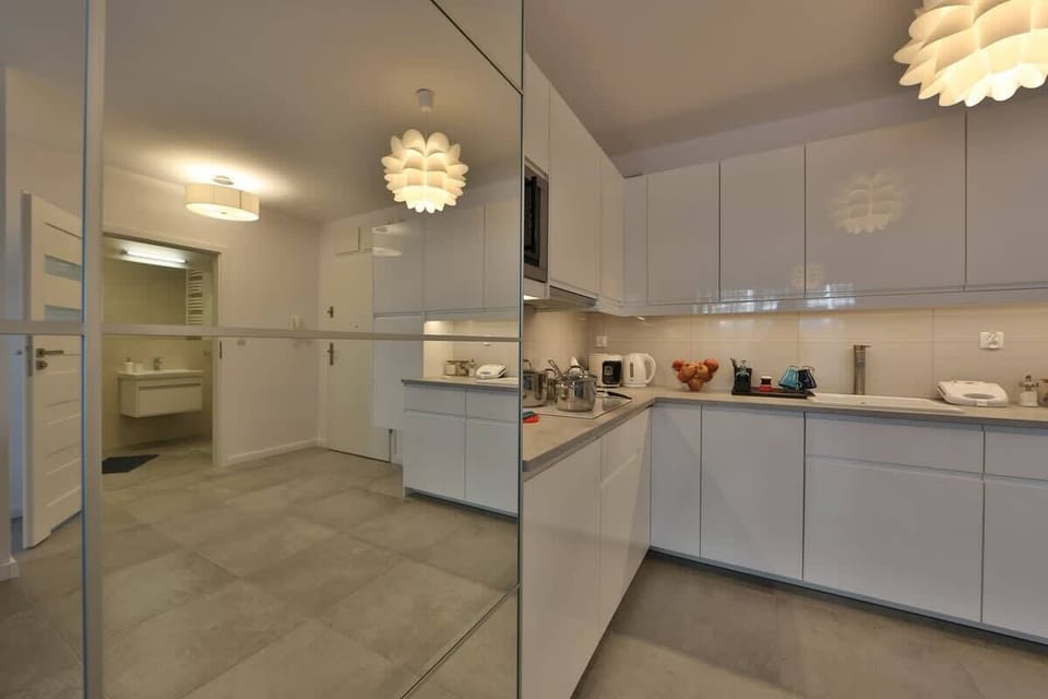 A sleek kitchenette with white cabinetry, integrated appliances, and under-cabinet lighting.