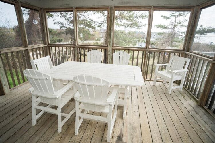 Enjoy your morning coffee or evening meals at this screened porch, where natural light pours in and peaceful views of surrounding greenery create a serene retreat for relaxation.
